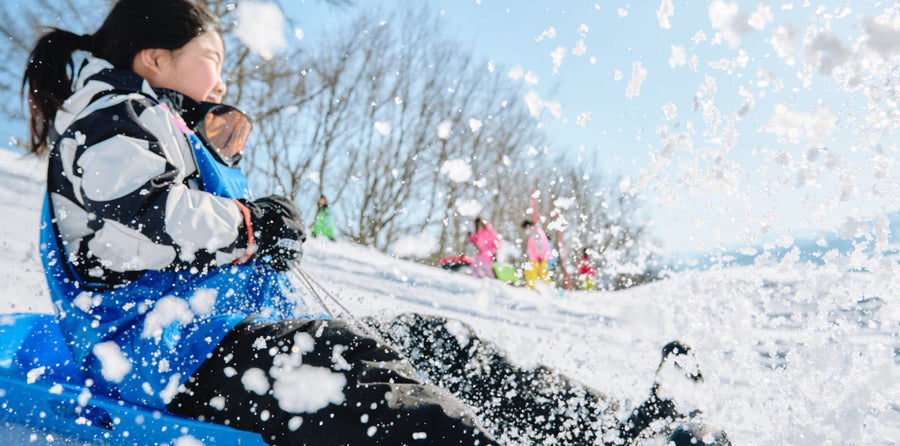 雪の中をそりで滑る子ども達横顔